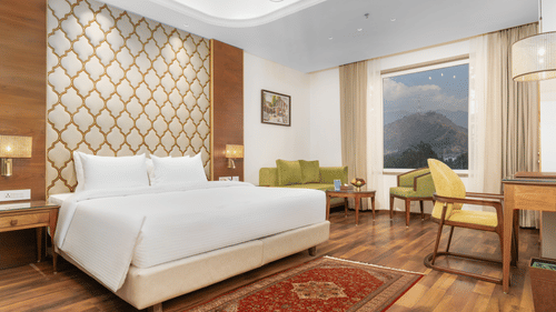 An image of our Deluxe Room with a double bed, a writing desk and a carpeted floor - Sarovar Premiere, Srinagar 